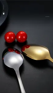Macro detail of mirror-polished gold and silver spoons on a dark textured surface