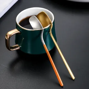 Cucchiai da caffè appesi in acciaio inossidabile oro e argento sul bordo di una tazza