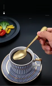 Golden stainless steel dessert spoon held over a coffee cup for stylish dining
