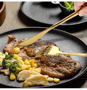 Macro detail of hand holding gold stainless steel cutlery set slicing a steak on a plate