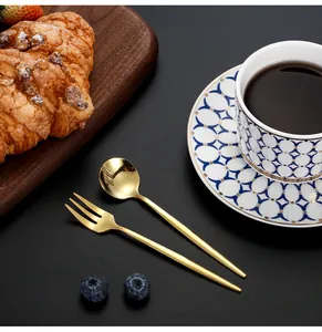 Close-up of golden stainless steel dessert spoon and fork on a matte black table