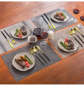 Détail d'un ensemble de couverts de luxe noir et or sur une table en bois rustique