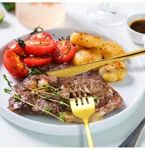 Gros plan d'un ensemble de couverts dorés en acier inox sur un plat de steak
