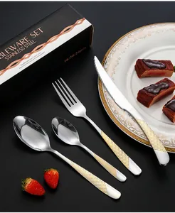 Détail d'un service de couverts en acier inoxydable avec manches dorés dans un coffret cadeau
