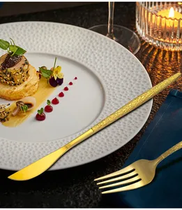 Macro detail of hammered gold stainless steel cutlery on a luxury dining table setup