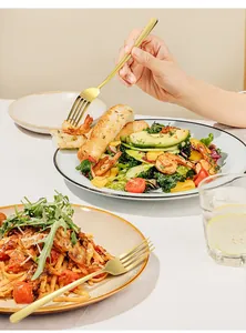 Detail van elegante gouden roestvrijstalen vorken geserveerd met garnalensalade en pasta