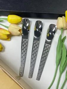 Détail de trois cuillères à dessert en acier inoxydable avec manches gravés de motifs de feuilles