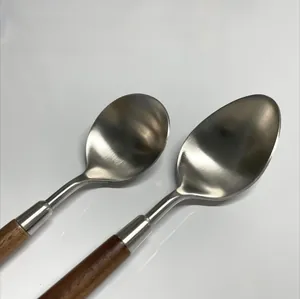 Close-up of brushed stainless steel spoons with vintage walnut wood handles and smooth edges