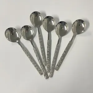 Detailed view of six stainless steel spoons with daisy embossed patterns and mirror finish