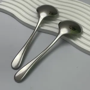 Macro view of two polished stainless steel round soup spoons with mirror finish