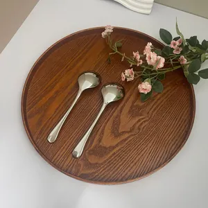 Detail of two hammer-textured 304 stainless steel spoons on a round wooden tray