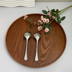 Polished stainless steel round spoons with hammered finish on dark wood tray