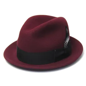 Detail of burgundy wool fedora hat with black grosgrain ribbon and spotted feather accent