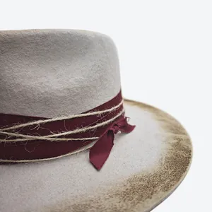 Detailed close-up of wool felt jazz hat with burnt edges and burgundy ribbon decor