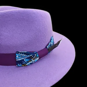 Dettaglio cappello in lana viola con nastro paisley e decorazione in piuma naturale