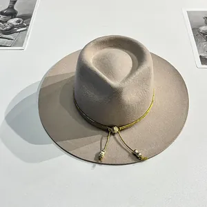 Dettaglio cappello in lana con finiture in filo dorato e accenti metallici dorati