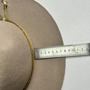 Dettaglio della tesa di 10 cm di un cappello in lana beige con cordoncino dorato