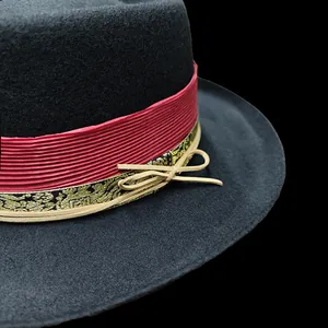 Detail van zwarte wollen hoed met rood lint, jacquardband en strik als versiering