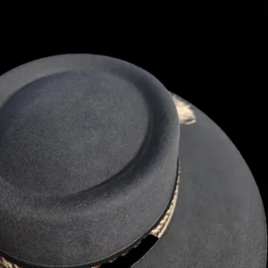 Dettaglio di un cappello di feltro di lana grigio scuro con nastro intrecciato e piuma