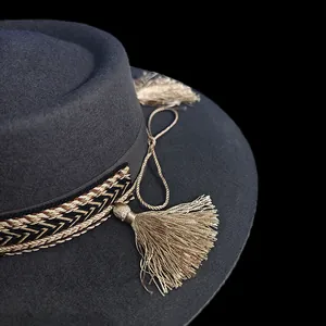 Dettaglio cappello in feltro di lana grigio con nappe dorate e nastro intrecciato chic
