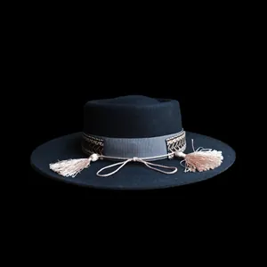Dettaglio cappello di lana con fascia etnica intrecciata e nappe di seta su feltro nero