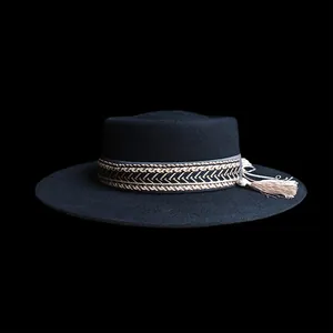 Dettaglio di un cappello di lana nero con fascia intrecciata oro e nappe decorative