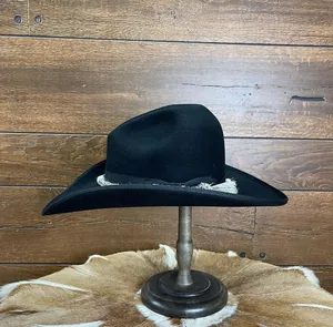 Close-up of black wool felt fedora with elegant white tassel fringe on wooden hat stand