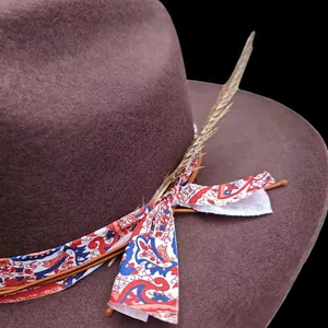 Detalle de un sombrero de fieltro marrón con cinta floral étnica y adorno de pluma natural