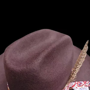 Primer plano de sombrero de fieltro marrón con pluma natural y cinta de estilo étnico