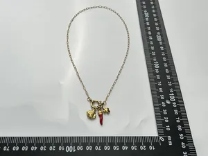 Detail of 18K gold plated necklace featuring sea shell, red horn, and elephant charms