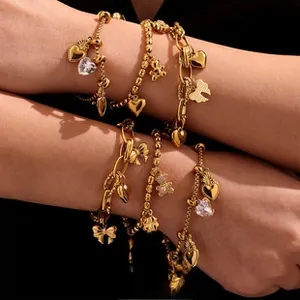 Detail of gold layered bracelets featuring heart, teddy bear and bow charms on model