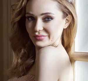 Close-up of elegant crystal tiara and single diamond stud earrings on a model