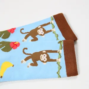 Detailed close-up of light blue baby socks with cartoon monkeys and tropical banana patterns