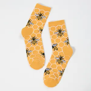 Detail of yellow knit crew socks with white honeycomb patterns and realistic bee designs