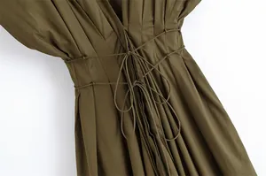 Detail der plissierten olivgrünen Stoffstruktur und Taillenbindung am Kleid