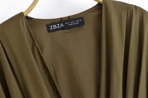 Detail des V-Ausschnitts und des schwarzen gewebten Größenetiketts am olivgrünen Kleid