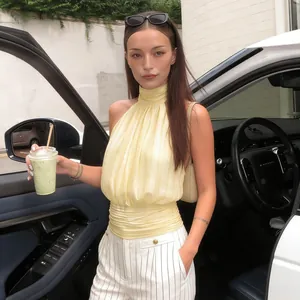 Détail du haut licou jaune élégant avec plis et pantalon rayé à la mode