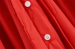 Detail der weißen Knöpfe und präzisen Nähte am roten, schmal geschnittenen Kleid