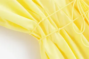 Detailaufnahme des gelben Kleides mit Kordelzug-Taille und feiner Stoffstruktur