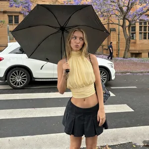 Détail du haut court licou jaune plissé et de la mini-jupe plissée noire tendance