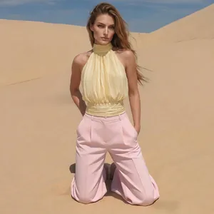 Détail du haut plissé jaune à licou et du pantalon large rose pour un look élégant