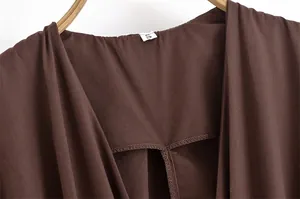 Makroansicht des V-Ausschnitts und S-Labels auf dem dunkelbraunen Kleid-Stoff