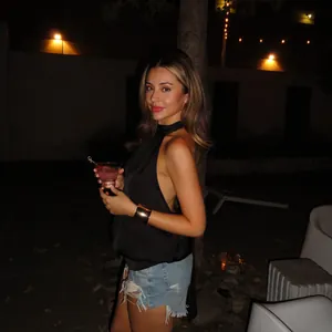Détail d'un haut licou noir chic avec un short en jean et un bracelet manchette doré élégant