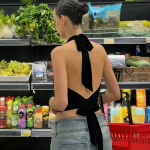 Détail d'un haut dos nu en velours noir avec un design à double nœud papillon au dos