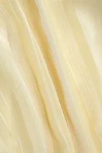 Gros plan sur un tissu mousseline jaune clair plissé avec texture verticale élégante
