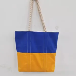 Detail view of large tote bag featuring blue and yellow color block design and rope handles