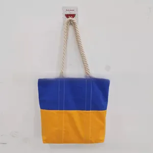 Detail of canvas tote bag with blue and yellow contrast stitching and cotton rope handles