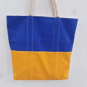 Detail of blue and yellow canvas tote bag with thick white rope handles for travel