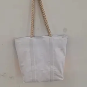 Detailed view of a white canvas tote bag with thick rustic rope handles and minimalist design