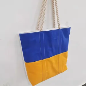 Detail of blue and yellow tote bag with thick braided rope handles and canvas texture